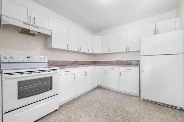a kitchen with granite countertop white cabinets and white appliances