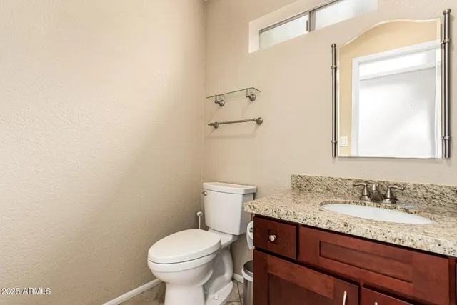 a bathroom with a granite countertop toilet sink and mirror