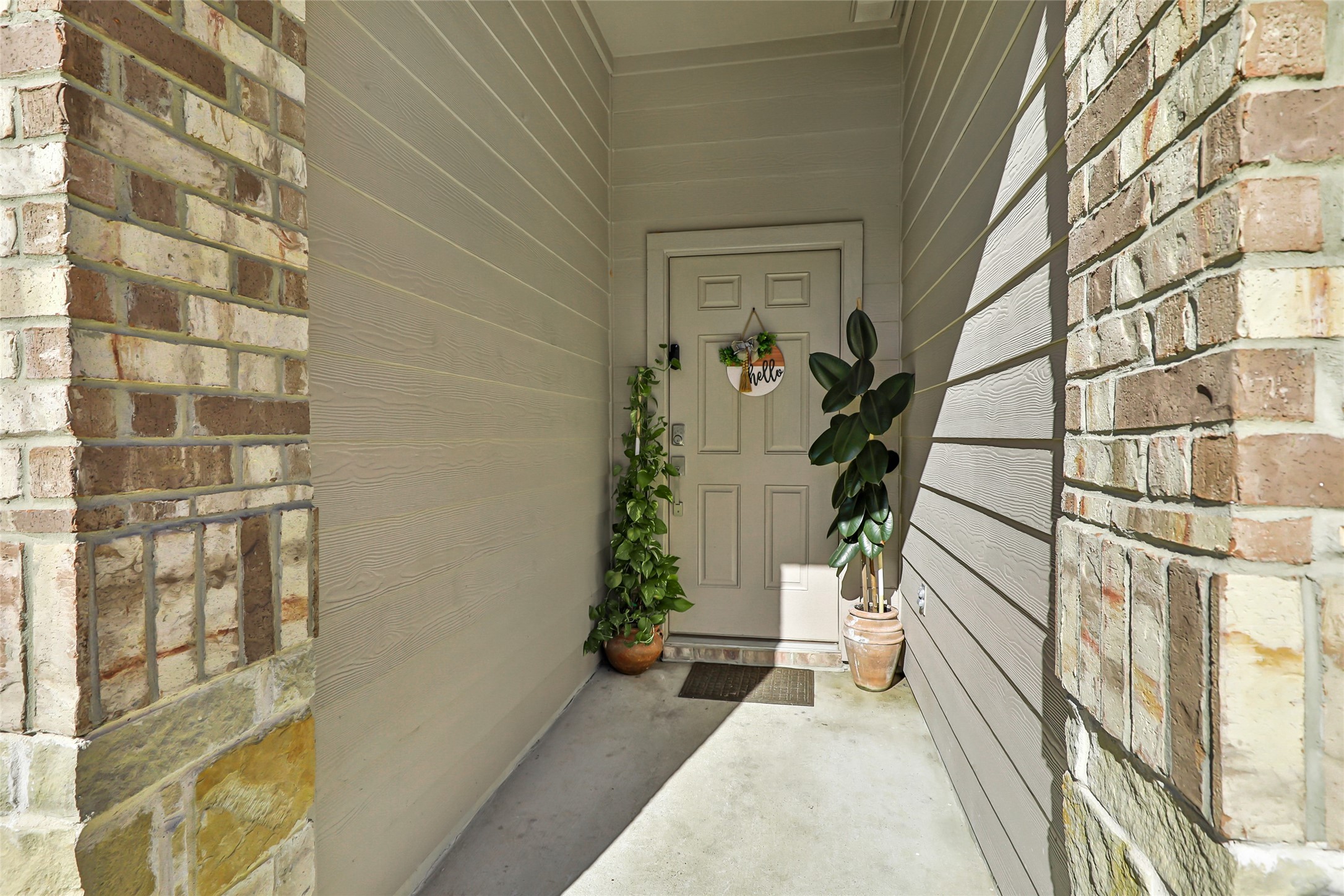 811 Republic Road New Caney, TX 77357 - Photo 4 of 37 This welcoming entryway features a covered porch with brick accents and two potted plants flanking the front door, providing a cozy and inviting first impression.