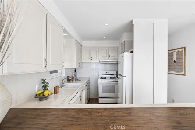 a kitchen with stainless steel appliances granite countertop a refrigerator sink stove and white cabinets