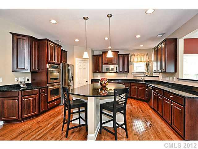 265 Lorraine Road, Unit 15 Fort Mill, SC 29708 - Photo 4 of 16 a kitchen with stainless steel appliances granite countertop wooden cabinets a refrigerator a sink a stove and chairs