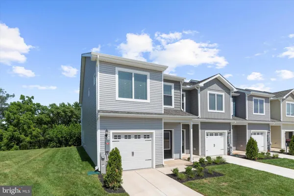 a view of a white house next to a yard with large trees
