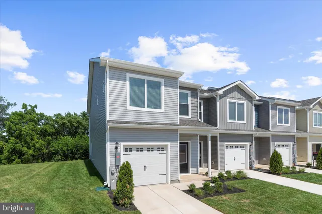 a view of a white house next to a yard with large trees