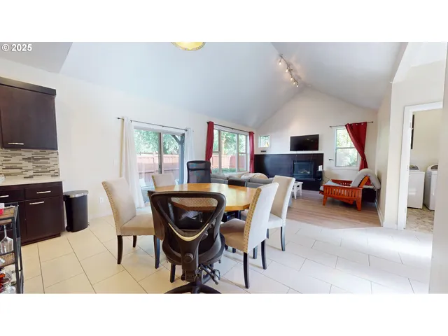 a living room with furniture a flat screen tv and a refrigerator