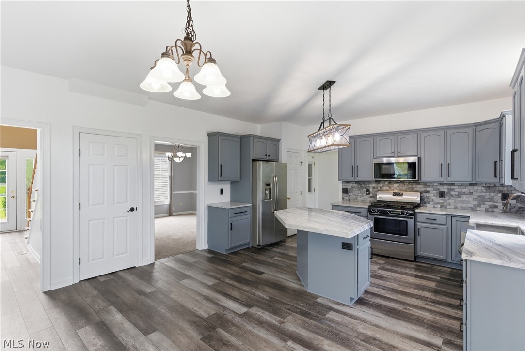 11678 Dunham Road Northfield, OH 44067 - Photo 6 of 38 Kitchen featuring grey cabinetry, stainless steel appliances, a center island with countertop seating, and wood-finish flooring