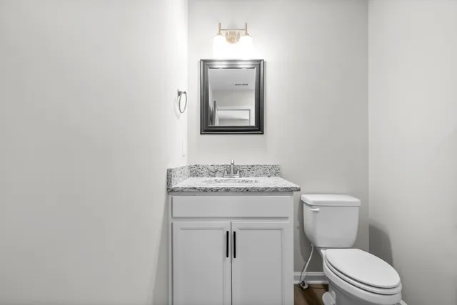 a bathroom with a granite countertop toilet sink and mirror