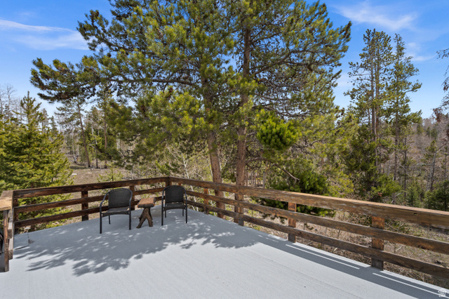 4725 Pine Ridge Road Evanston, UT 82930 - Photo 50 of 82 Expansive outdoor deck with natural wood railing overlooking a pine forest