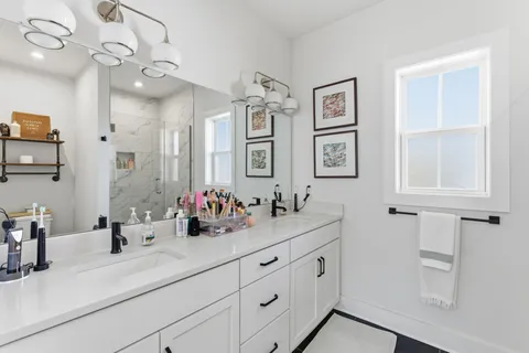 a bathroom with double vanity sinks a vanity a lamp and a mirror