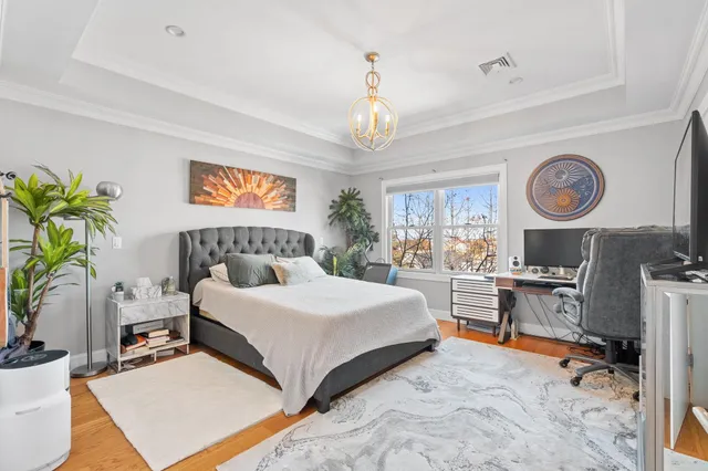 a spacious bedroom with a bed a chandelier and a window