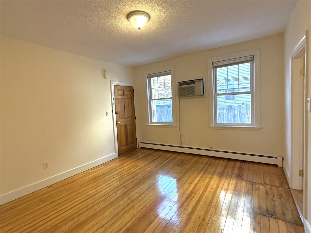 18 Roberts Street, Unit 1 Brookline, MA 02445 - Photo 3 of 10 an empty room with wooden floor and windows