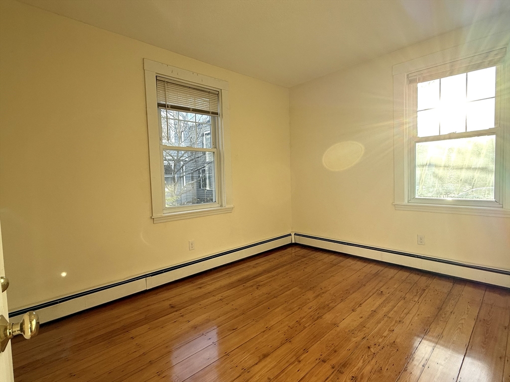 18 Roberts Street, Unit 1 Brookline, MA 02445 - Photo 8 of 10 a view of an empty room with wooden floor and a window