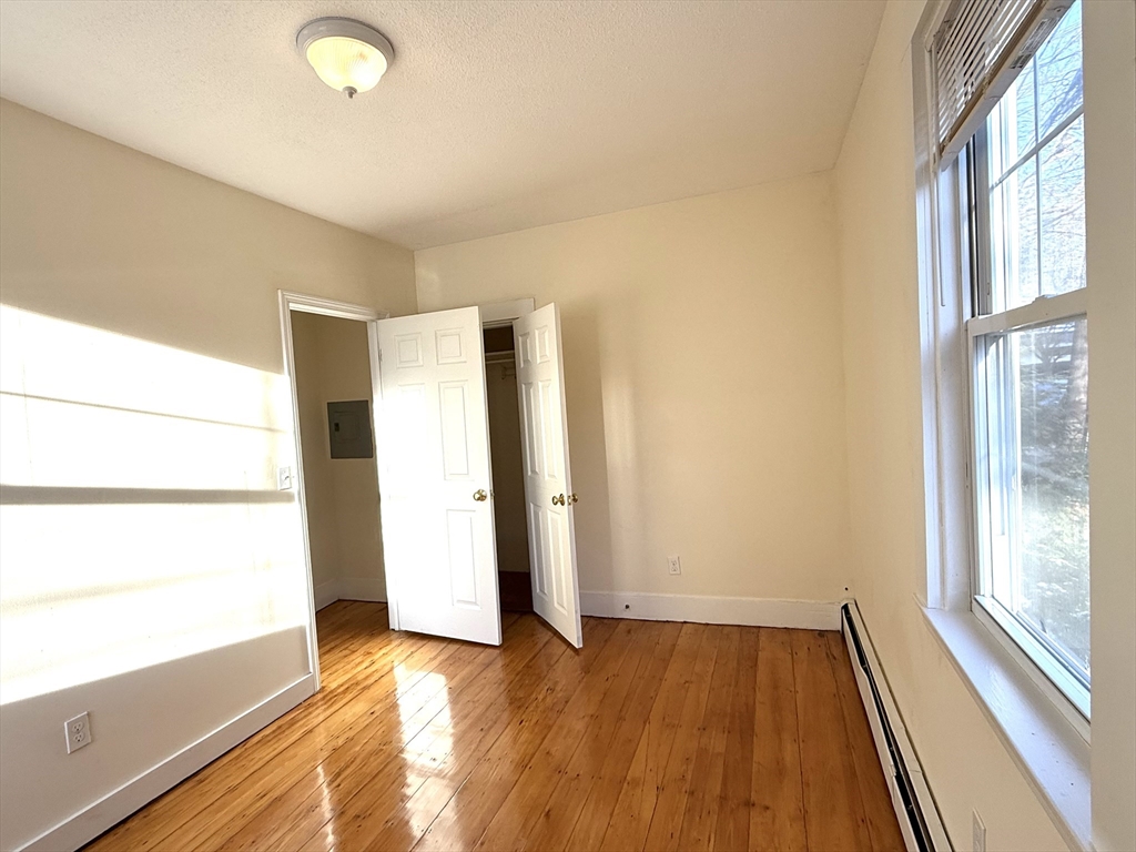 18 Roberts Street, Unit 1 Brookline, MA 02445 - Photo 9 of 10 a view of an empty room with wooden floor and a window