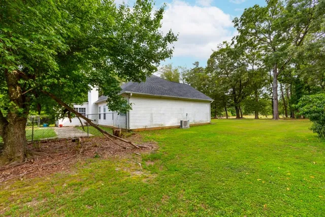 a backyard of a house with plants and large tree