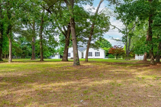 a view of a house with a big yard and large trees