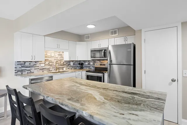 a kitchen with granite countertop a refrigerator and wooden floor