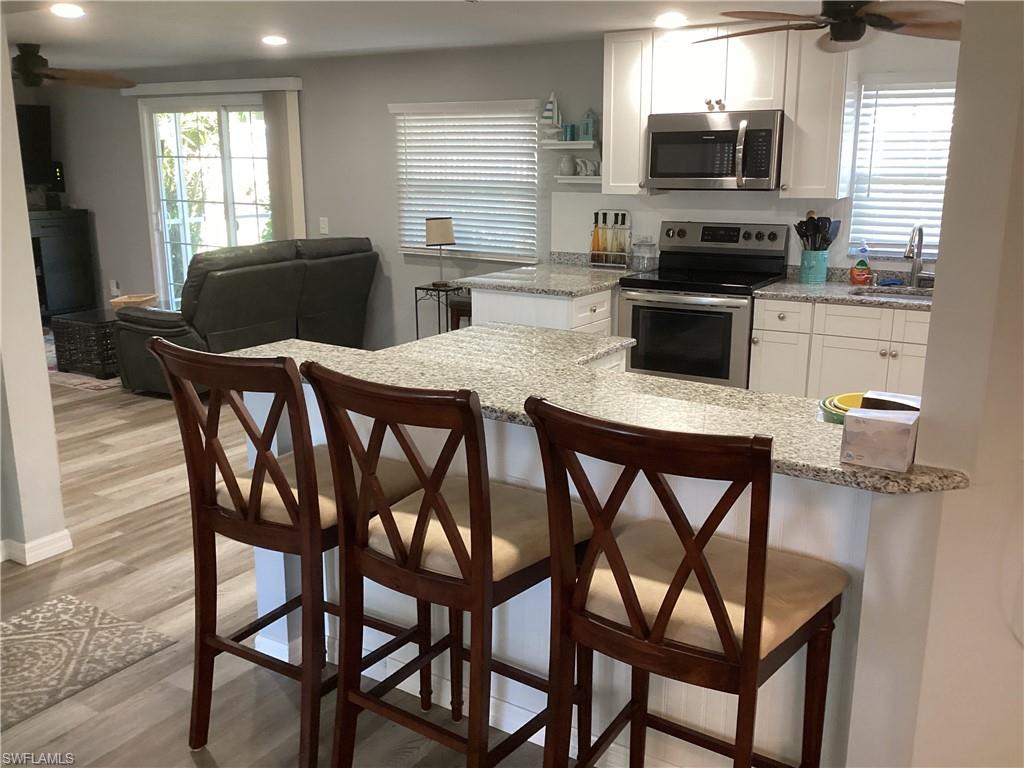 4 Chateau Way Naples, FL 34112 - Photo 11 of 45 a kitchen with stainless steel appliances granite countertop a dining table chairs microwave and sink