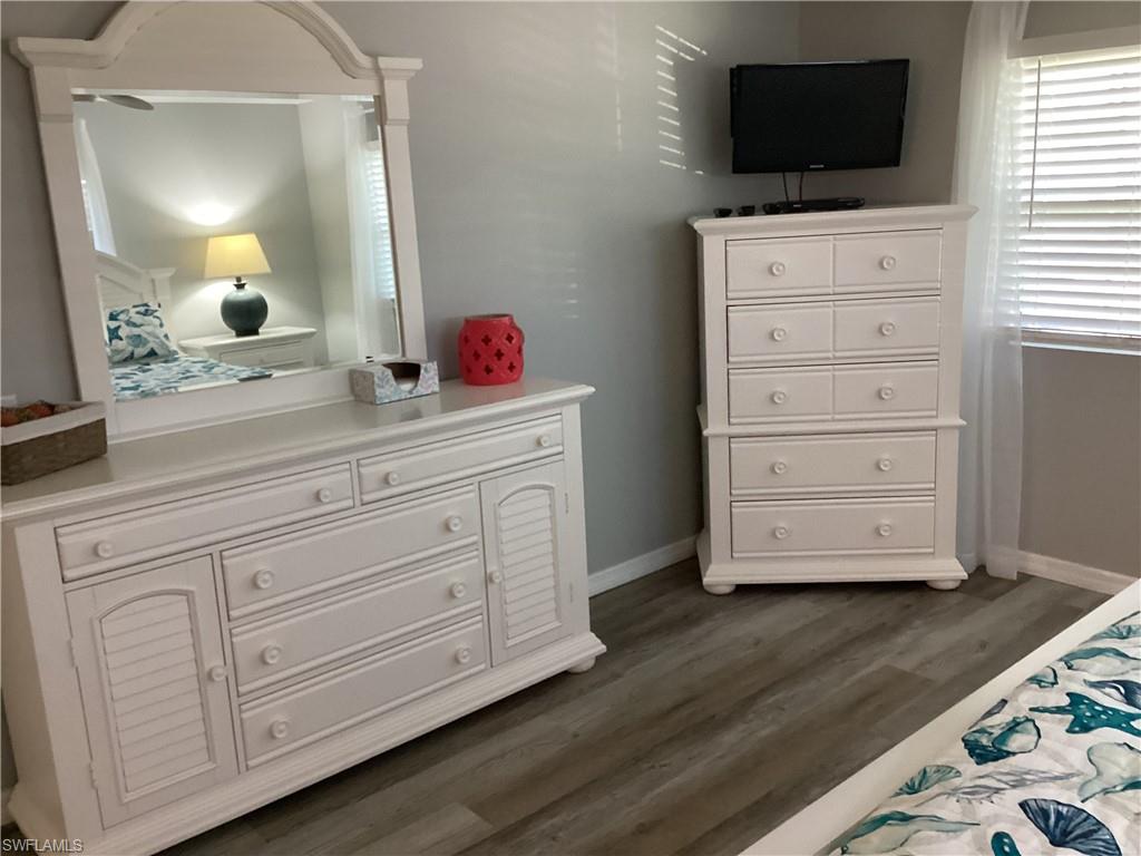 4 Chateau Way Naples, FL 34112 - Photo 18 of 45 a room with wooden floor a dresser and a flat screen tv