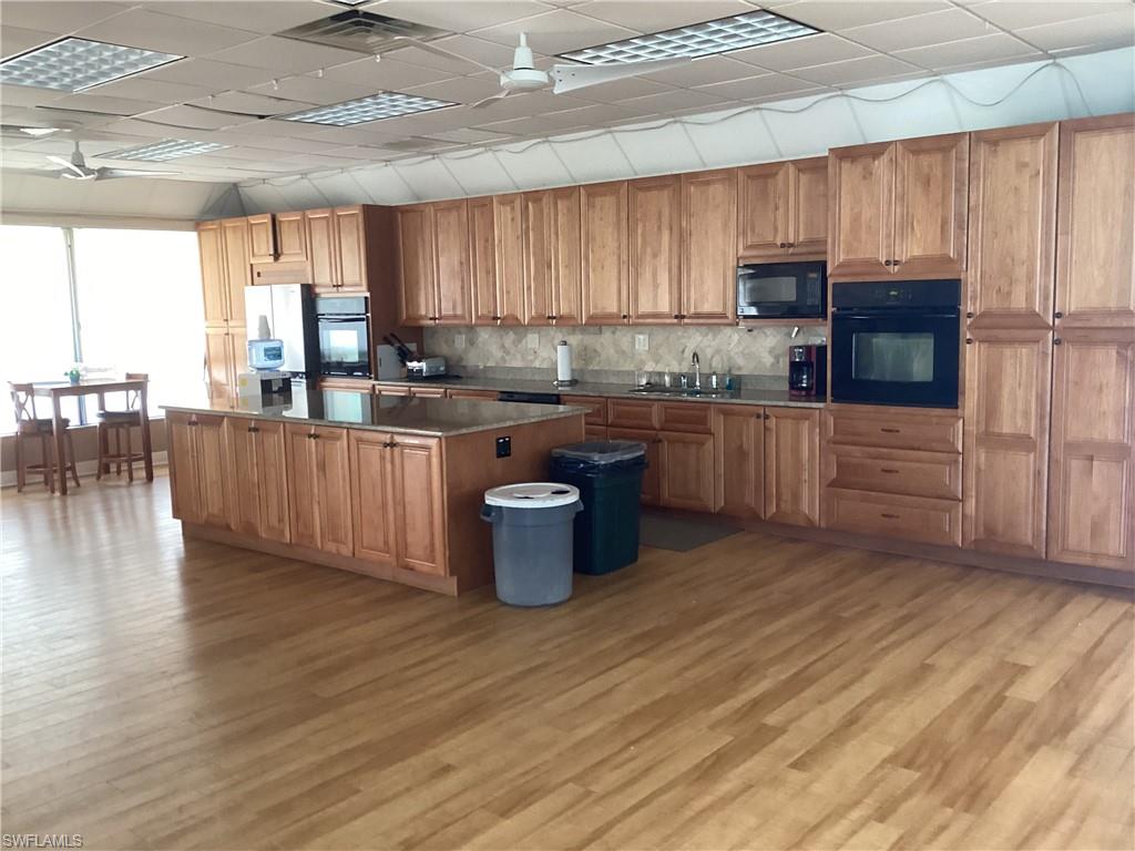 4 Chateau Way Naples, FL 34112 - Photo 34 of 45 a kitchen with stainless steel appliances wooden floors and wooden cabinets