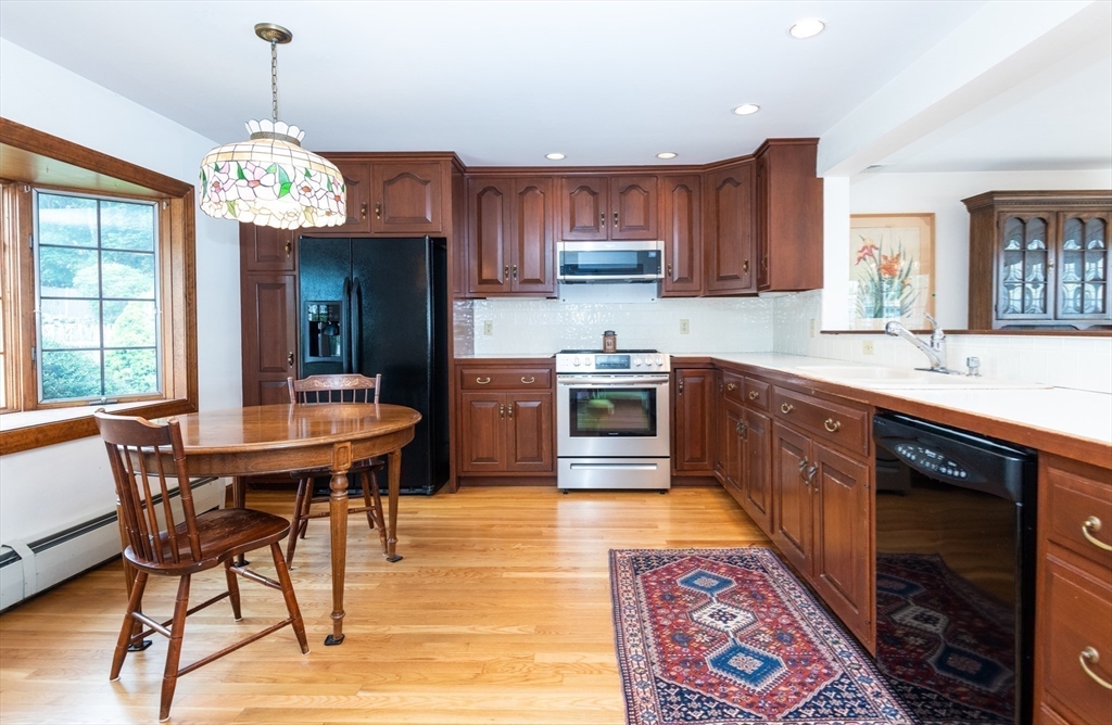 97 Pitman Road Marblehead, MA 01945 - Photo 27 of 37 a open kitchen with stainless steel appliances granite countertop a stove a sink dishwasher a dining table and chairs with wooden floor