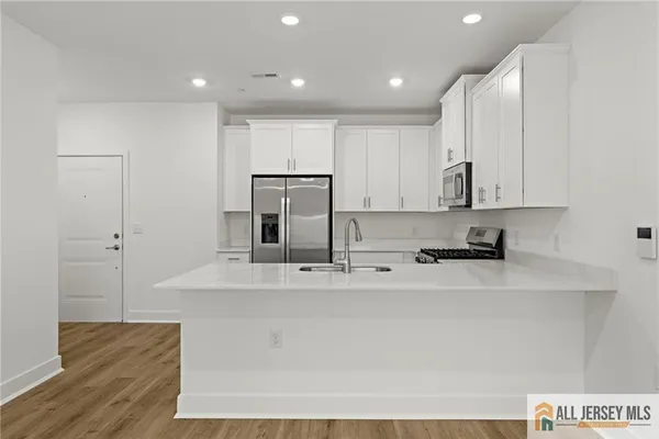 a large white kitchen with wooden floor