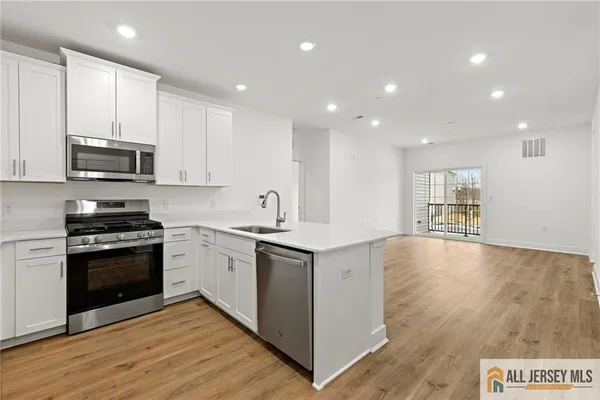 a large kitchen with stainless steel appliances granite countertop a stove a sink and a microwave
