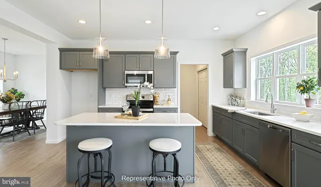 a kitchen with stainless steel appliances granite countertop a sink a stove a dining table and chairs