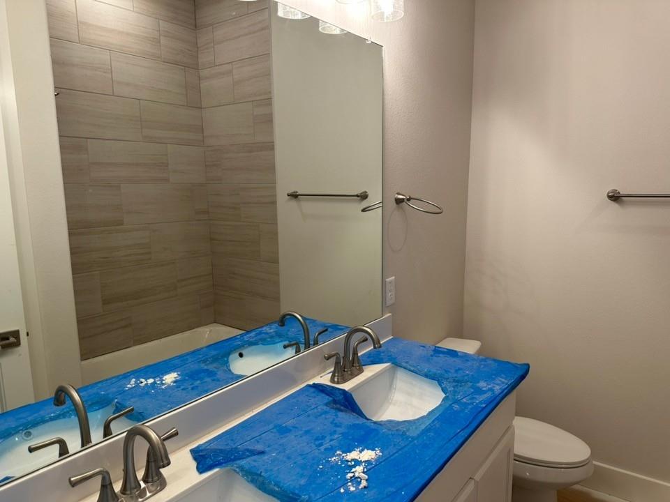 410 Cobb Road Leonard, TX 75452 - Photo 21 of 24 Contemporary bathroom featuring a double vanity with undermount sinks, brushed nickel fixtures, a full-width mirror, and a tiled tub surround
