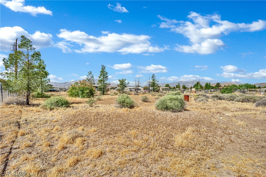 4361 Maple Road Pahrump, NV 89048 - Photo 44 of 46 A spacious, undeveloped parcel offering clear mountain views under a bright, cloud-dotted sky.