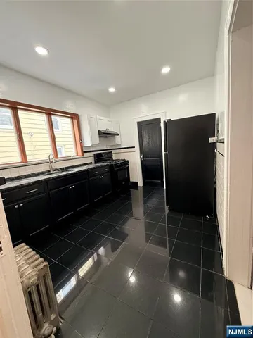 a kitchen with granite countertop a refrigerator and a stove top oven