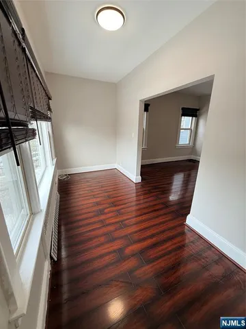 a view of an empty room with wooden floor and stairs