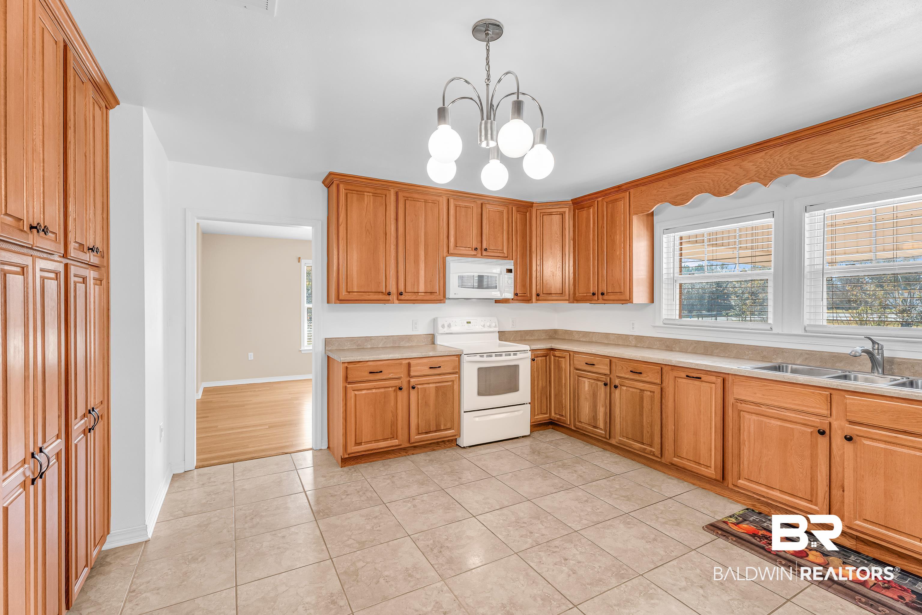 22095 8th Street Silverhill, AL 36576 - Photo 20 of 42 Kitchen featuring white appliances, suspended lighting, light tile patterned floors, and healthy amount of natural light