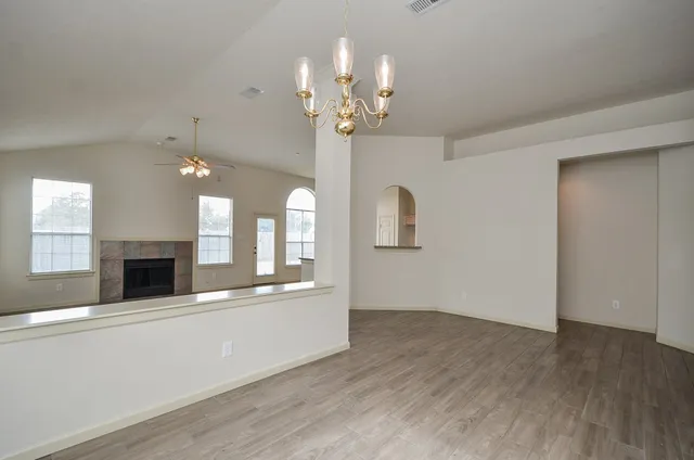 a view of an empty room with a fireplace and chandelier