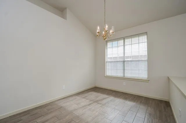 an empty room with chandelier fan and windows