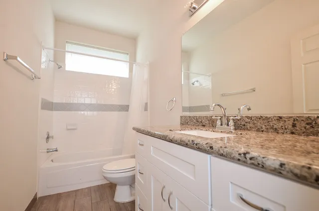 a bathroom with a granite countertop toilet a sink and a bathtub
