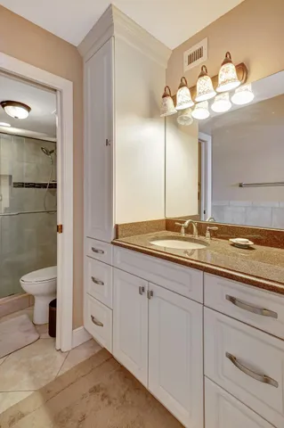 a bathroom with a granite countertop sink a toilet and a mirror