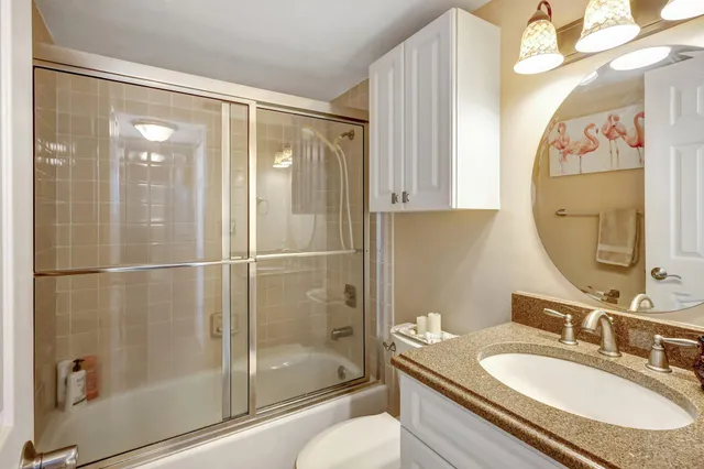 a bathroom with a granite countertop sink toilet and shower