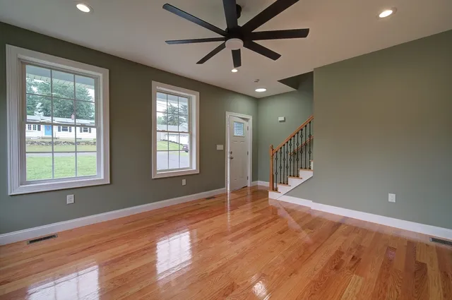 a view of an empty room with a window and wooden floor