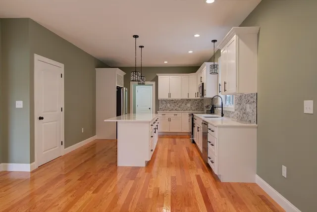 a large kitchen with stainless steel appliances a large counter top a sink a refrigerator and a window