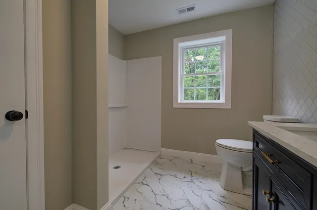 a bathroom with a sink a toilet and shower
