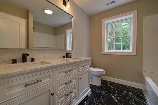 a bathroom with a double vanity sink a toilet and a window