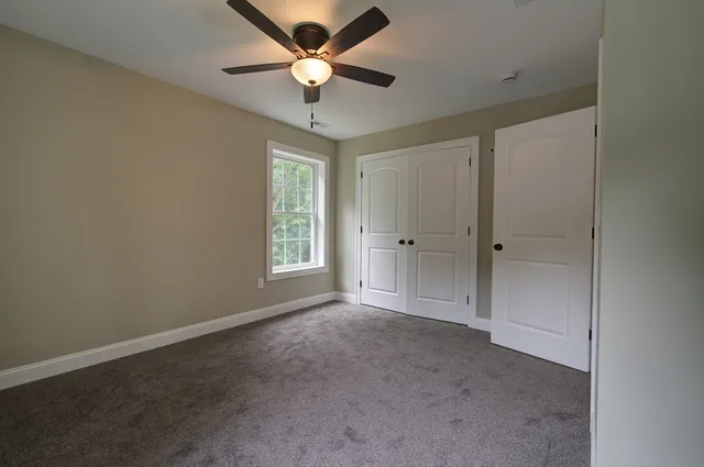 an empty room with a ceiling fan and a window