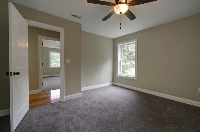 a view of an empty room with window closet area and chandelier fan