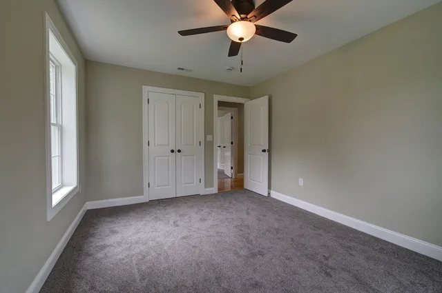 an empty room with windows and fan