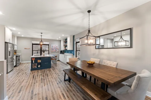 a living room with stainless steel appliances granite countertop furniture wooden floor and a chandelier