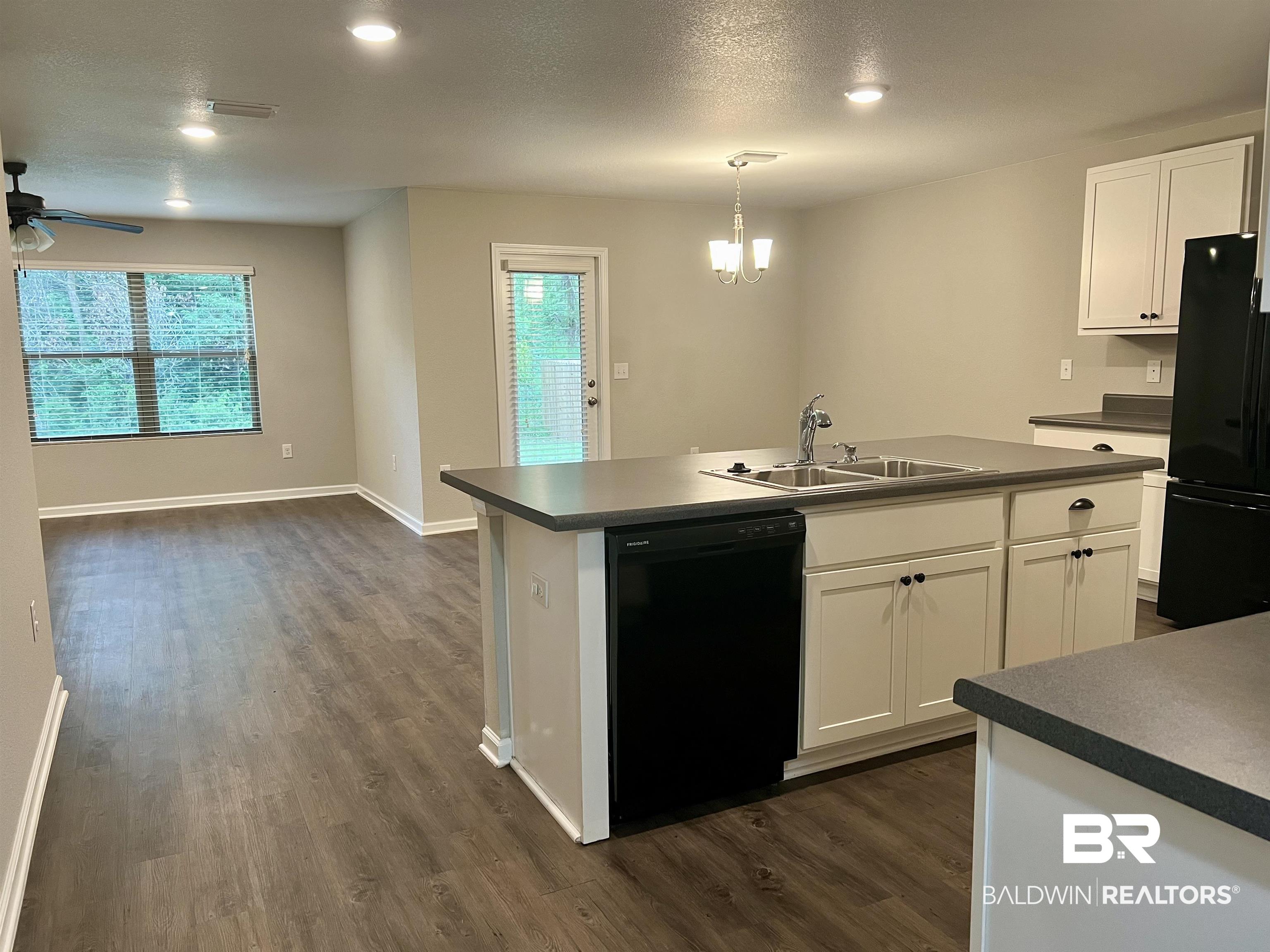 1612 Abbey Loop Foley, AL 36535 - Photo 8 of 30 Kitchen with ceiling fan with notable chandelier, black appliances, an island with sink, sink, and dark wood-type flooring