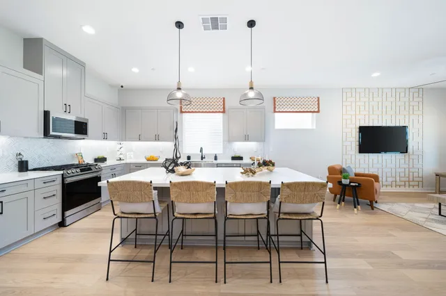 a kitchen with stainless steel appliances kitchen island granite countertop a sink a stove a dining table and chairs