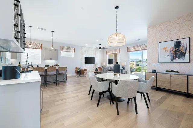 a dining room with wooden floor a chandelier a wooden table and chairs