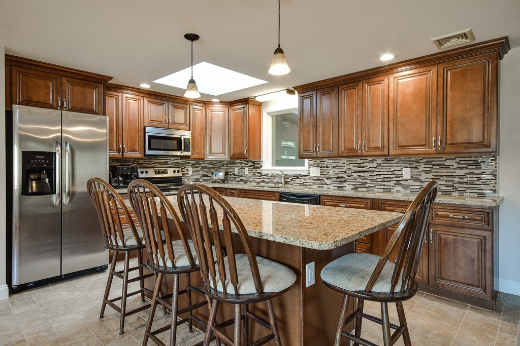18 Gary Road Needham, MA 02494 - Photo 9 of 29 a kitchen with stainless steel appliances granite countertop a stove top oven a refrigerator a sink with a dining table and chairs