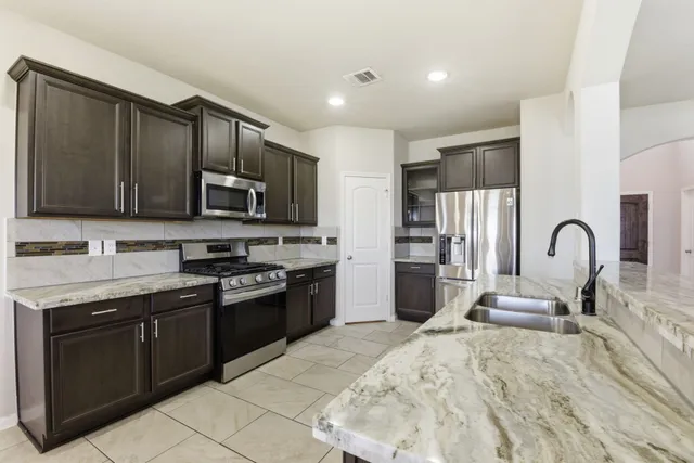 a kitchen with stainless steel appliances granite countertop a stove a sink and a microwave