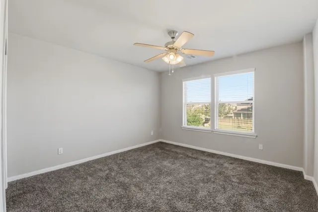 an empty room with a window and a fan